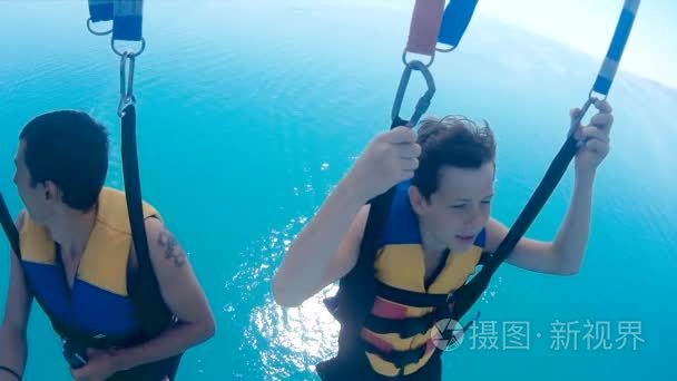 滑翔伞和帆伞运动的生活方式。男人和一个男孩在海上乘坐降落伞。极限运动第一人称视角视频