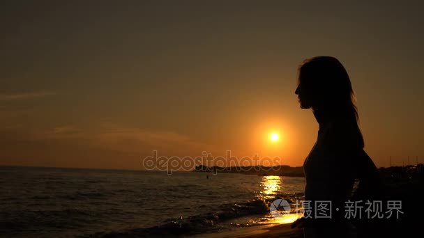 在海滩上考虑日落的女人剪影
