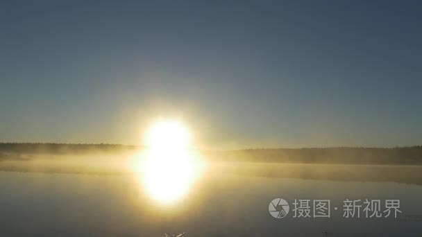 森林湖的夏天日落景色。查看与明亮的太阳湖上遥远的海角和晚霞倒映在平静的水面，在午夜的太阳。雾在月夜河上