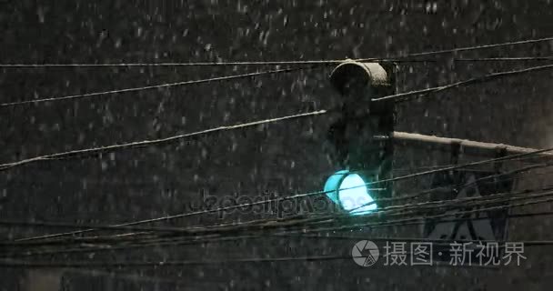 交通灯照耀在降雪期间。恶劣的天气，雨和湿的雪的道路上。思考的夜晚灯光。车头灯