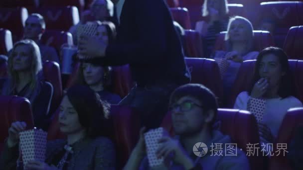 人们看电影在电影院电影院里放映的时候，男人正在他的座位