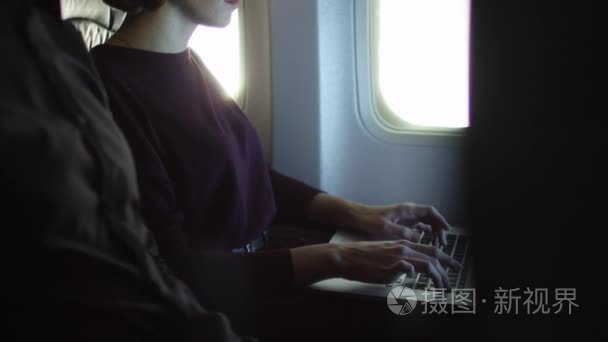年轻女子正在笔记本电脑内飞机的窗边