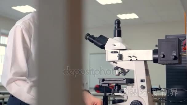 一位年轻科学家使用光学显微镜视频