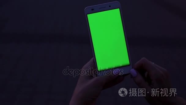 女人手触碰智能手机。带绿色的屏幕电话。绿色屏幕显示