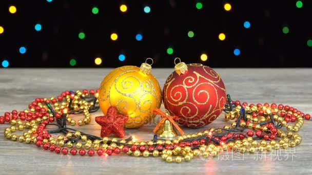 美丽的圣诞红和金色球和反对多彩闪烁花环在黑色背景上的木地板上的装饰品。无缝 loopable