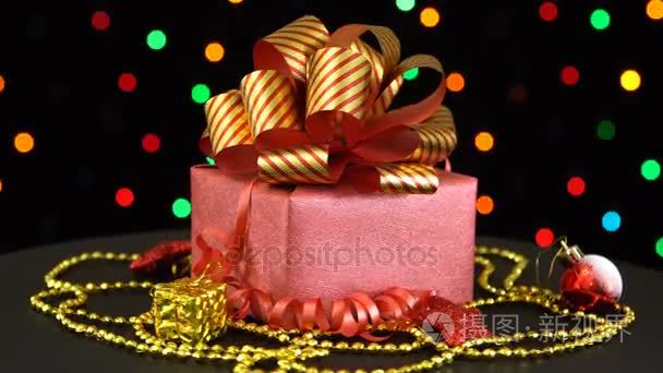 美丽的圣诞节礼品盒和旋转对多彩闪烁花环在黑色背景上的装饰品
