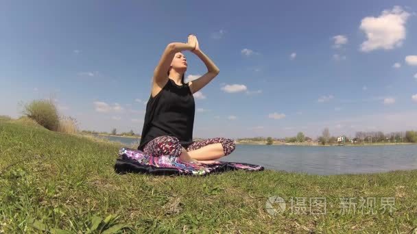 做瑜伽练习中自然湖附近的一个女孩