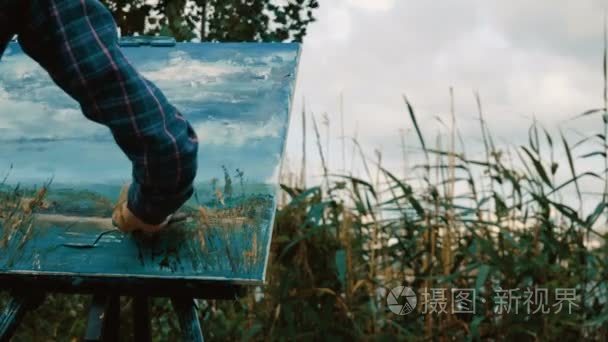 女手用油画颜料使用调色刀画水景观。4 k