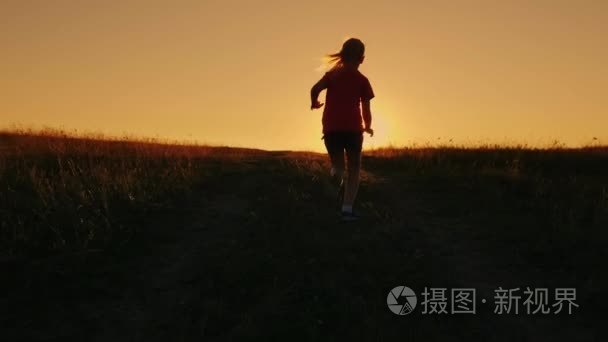 无忧无虑的女孩跑上山日落背景上。克服困难，第一的成绩