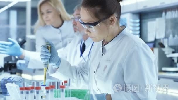 团队的研究科学家使用个人计算机 分析测试试验新一代药物数据和使用微管吸吮填补试管。他们工作在现代实验室  医疗中心视频