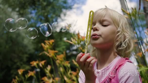可爱的金发小女孩，在夏天公园吹肥皂泡泡。慢动作。高清