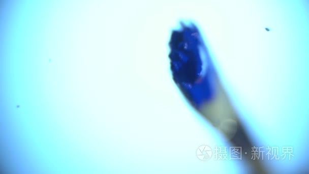 微距拍摄作为画笔慢慢与蓝色油漆玻璃涂料