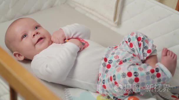 一个可爱的小婴儿望着镜头和快乐在白色的床单上