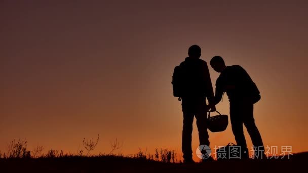 两人游客在日落时的剪影。黎明日出阳光旅游旅行男孩和男人