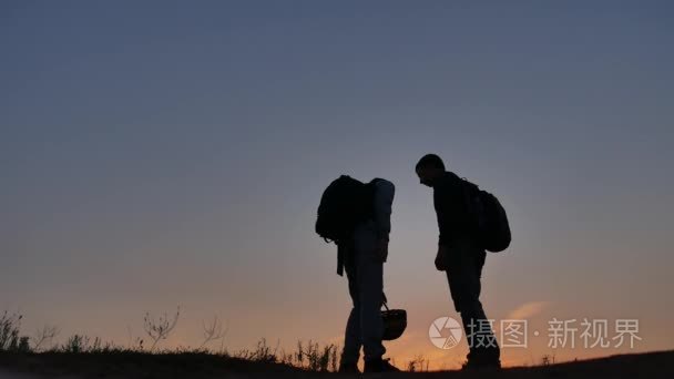 两人游客旅游在日落时的剪影。黎明日出阳光旅游男孩和男人