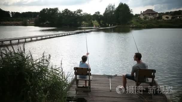 父亲和儿子花休闲渔业在池塘视频
