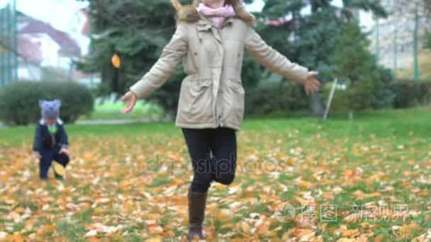 妈妈，儿子玩秋天叶子在园林公园。秋天的性质，户外游戏行走、 跑步沿着草和扔黄金箔。在 11 月的娱乐。儿童和母亲，家庭幸福