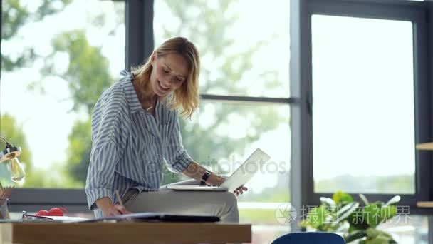 快乐的女学生，坐在桌子上，一边在线学习