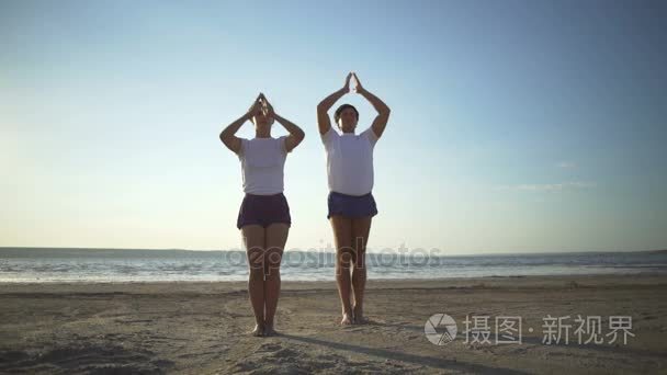 男人和女人做瑜伽椅子构成合十海滨日出快速慢动作