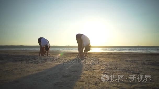 一群人练瑜伽构成海滨沙滩日落快速慢动作