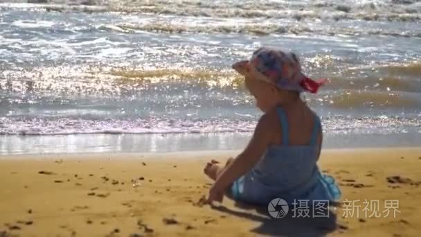 小女孩坐在沙滩上，在沙滩上画