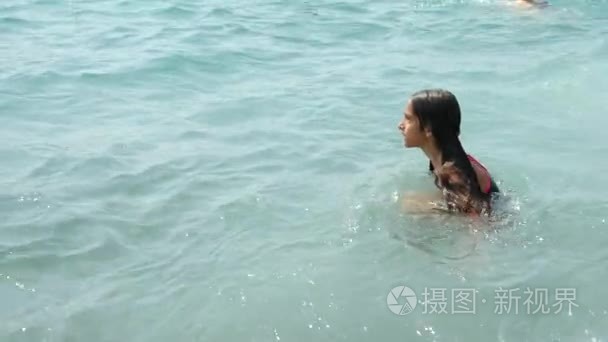 一位少女洒进海浪在海滩上。她追浪，非常高兴。4 k.慢动作