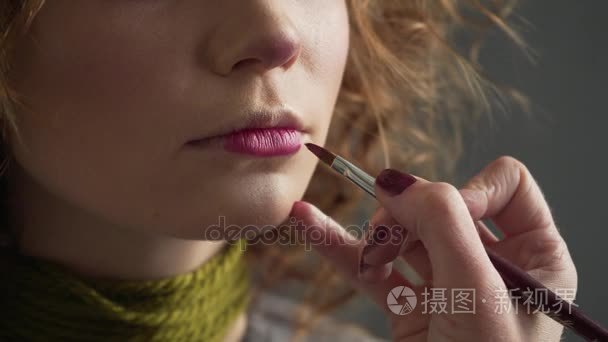 化妆师涂料为女孩的嘴唇。专业彩妆的模型。美丽的新娘妆