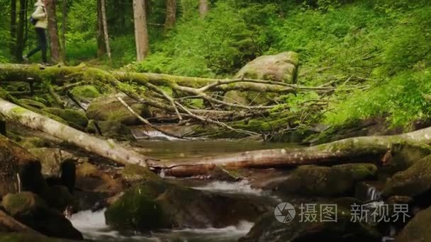 一个旅行者在一件羽绒服的女子，一条山涧河流穿越日志