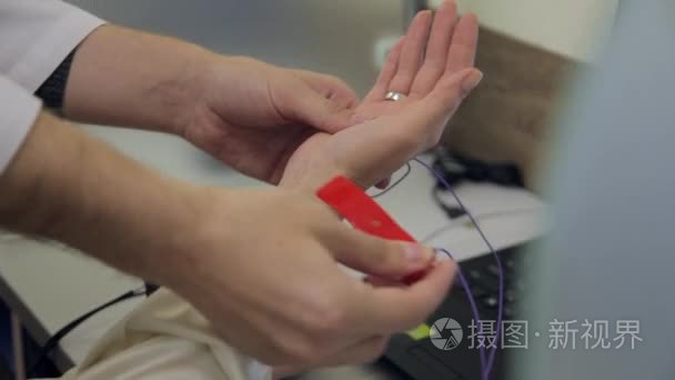 一位男医生将病人连接到创新的电子设备，为健康研究的手。新的医疗技术