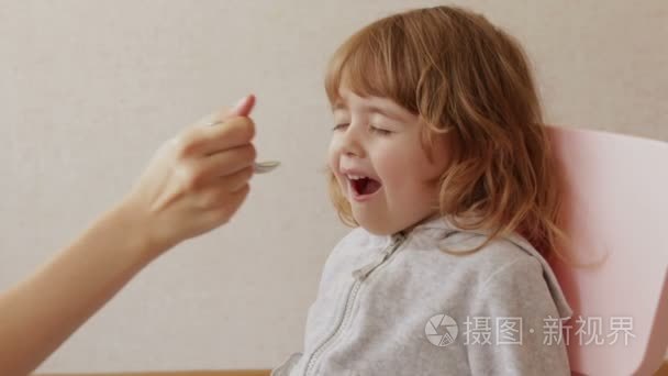 妈妈给小女孩的药。孩子喝苦的糖浆