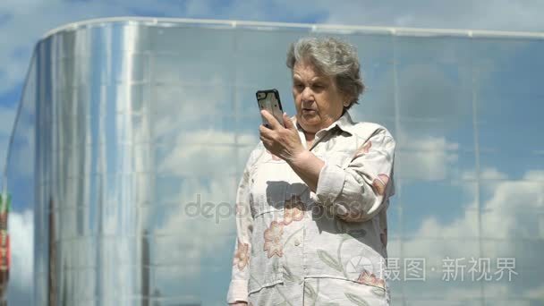 在户外使用智能手机的老妇会谈视频