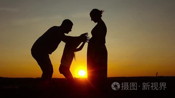 剪影，与母亲和父亲，在夕阳下，夏季家庭幸福的孩子。友好的家庭的概念