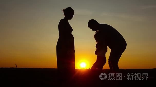 剪影，与母亲和父亲，在夕阳下，夏季家庭幸福的孩子。友好的家庭的概念
