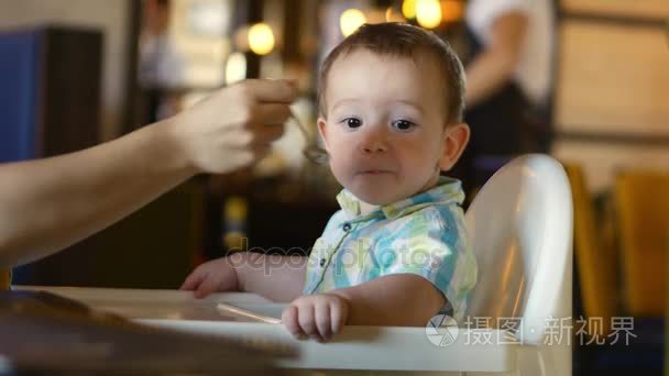 儿童和食物，母亲给婴儿食品从婴儿勺在一家餐馆，孩子沉迷和不肯吃。4 k视频