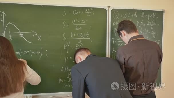 三个学生写上黑板在教室里的数学公式。俄罗斯学校