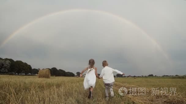 小男孩在一件白衬衫和一个小女孩，长头发，穿白裙子跑外地以满足彩虹视频