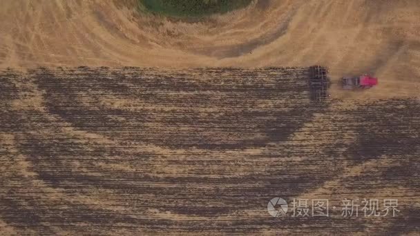 耕地的田野上空的无人机空中： 射击。红色的拖拉机清除字段在秋天