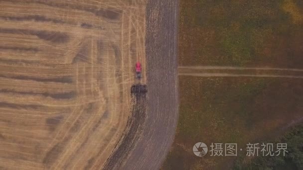 耕地的田野上空的空中 射击。红色的拖拉机清除字段在秋天