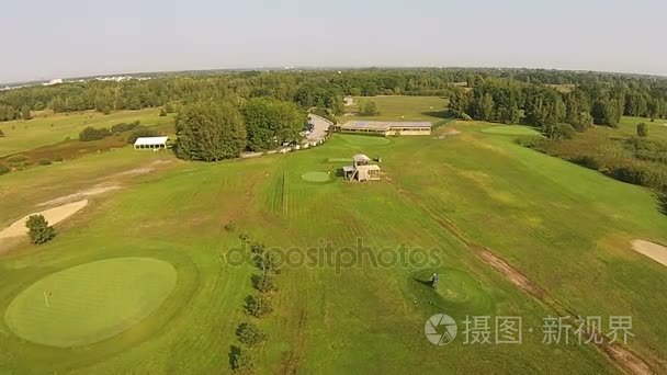 一架无人驾驶飞机飞过绿色高尔夫球场与高尔夫俱乐部大厦