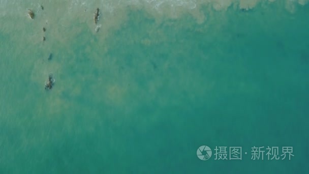 鸟瞰图波涛拍击在日落海滩，土地满足海