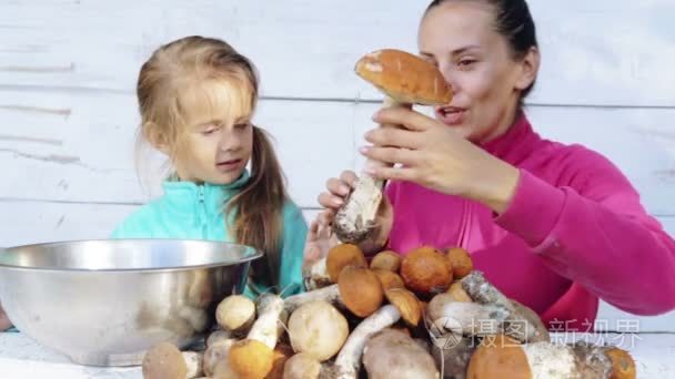 妈妈和女儿清洁新鲜采摘的蘑菇。一位母亲和她的孩子为清洗生态清洁食品的画像。食 煮食 环境友好性