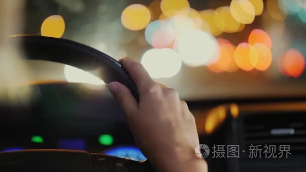 晚上在市内开车。女性双手放在方向盘上，视频与浅景深