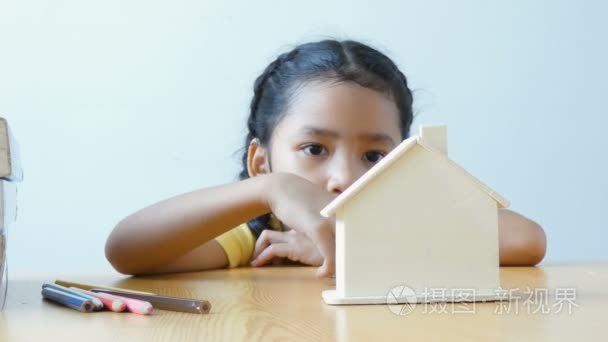 亚洲小女孩钱硬币投入为存钱买房子和房地产概念的明确房子银行隐喻