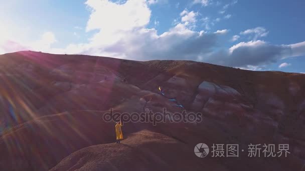 空中： 一个年轻的姑娘站在红色背景上她放风筝在高山的山。冒险在山上寻找自由的观念。更大的梦想女孩