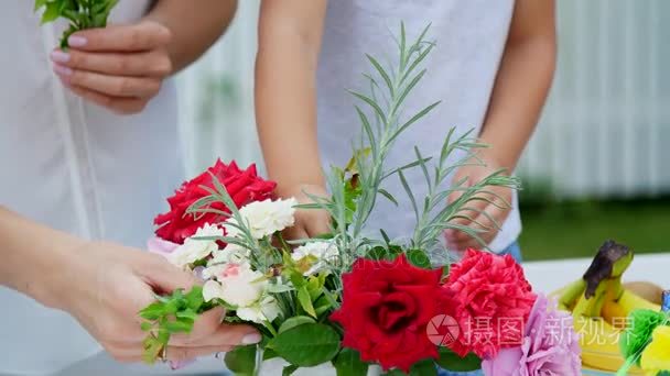 夏天，在花园，特写。妈妈带着四岁的儿子做一束鲜花。男孩喜欢它非常多，他是快乐，家庭花费他们的闲暇时间在一起