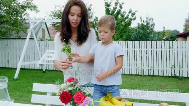 夏天，在花园里。妈妈带着四岁的儿子做一束鲜花。男孩喜欢也很多，他很高兴，开心，家人一起花费他们的闲暇时间