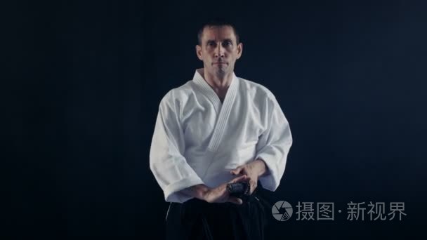 人像拍摄的合气道大师身穿传统武士袴衣服需要他日本刀鞘和与它的波动
