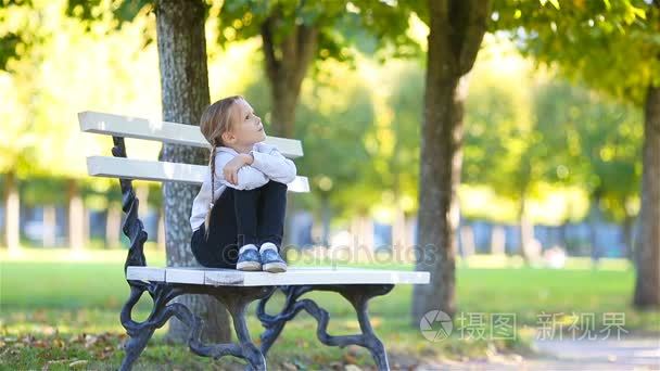 可爱的小女孩，在美丽的秋日户外活动。可爱的孩子，坐在室外公园的长凳上