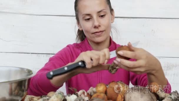 年轻漂亮的女人清洗新鲜的蘑菇。一个年轻的厨师女孩准备蘑菇的画像。自然，生态友好厨房