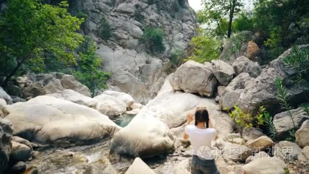 年轻游客女人拍照的美丽峡谷上她旅行期间的智能手机相机的